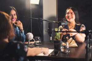 Three girls laughing during a podcast recording