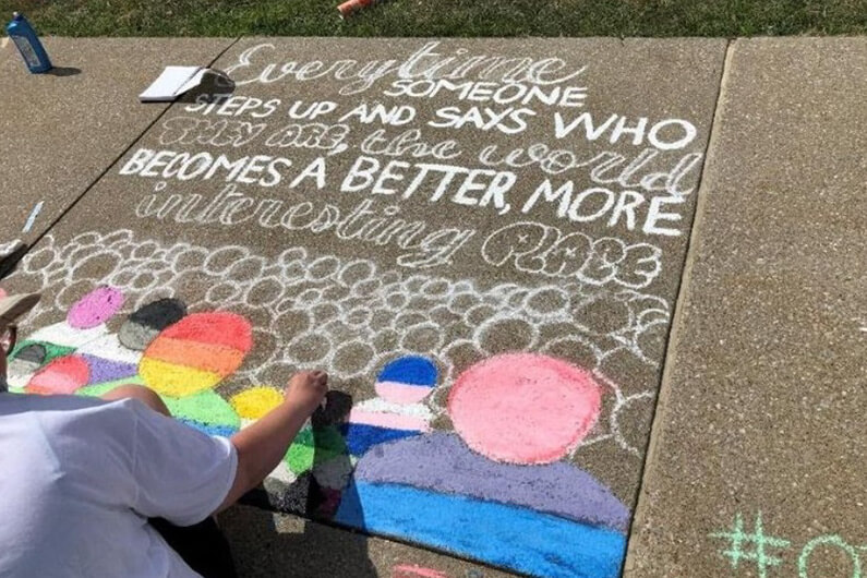 Woman drawing with chalk on sidewalk 